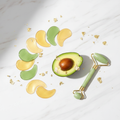 Flat lay of gold and avocado eye patches with avocado and jade roller on marble